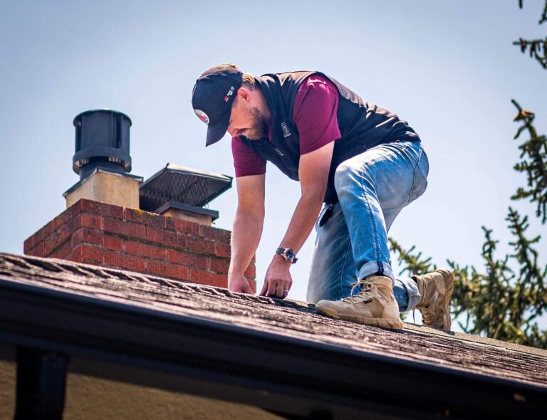 Summit Roofing crew member working on a Northern Colorado home roof beside a brick chimney
